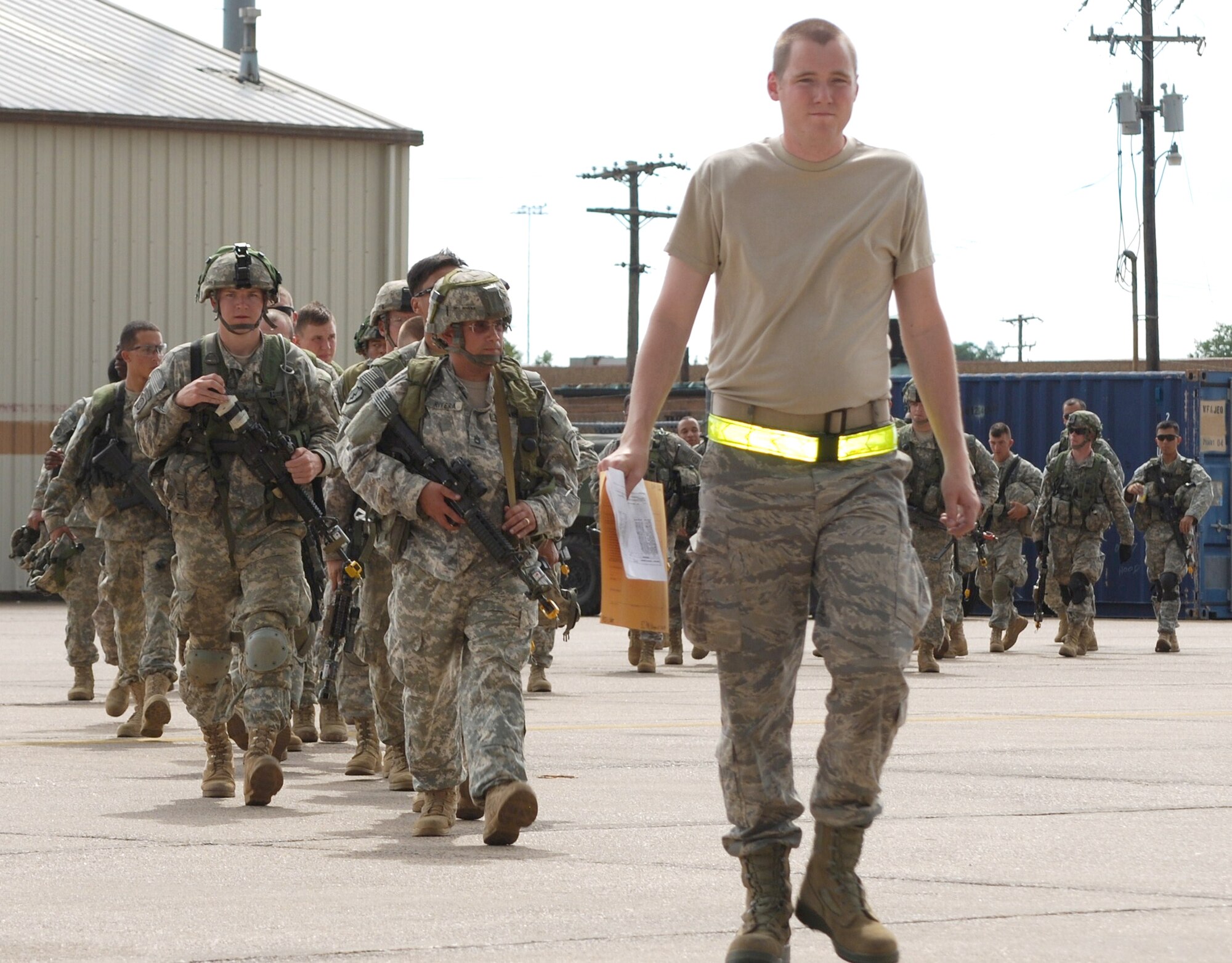 Airman First Class Collin Pinkerton-Morrow leads a group of Soldiers onto the flightline to board a C-130 Hercules departing to a forward operating location during a Joint Readiness Training Center exercise Oct. 18 at Alexandria International Airport in Lousiana. Airman Pinkerton-Morrow is with the 570th Global Mobility Squadron. (U.S. Air Force photo/Capt. Paradon Silpasornprasit)