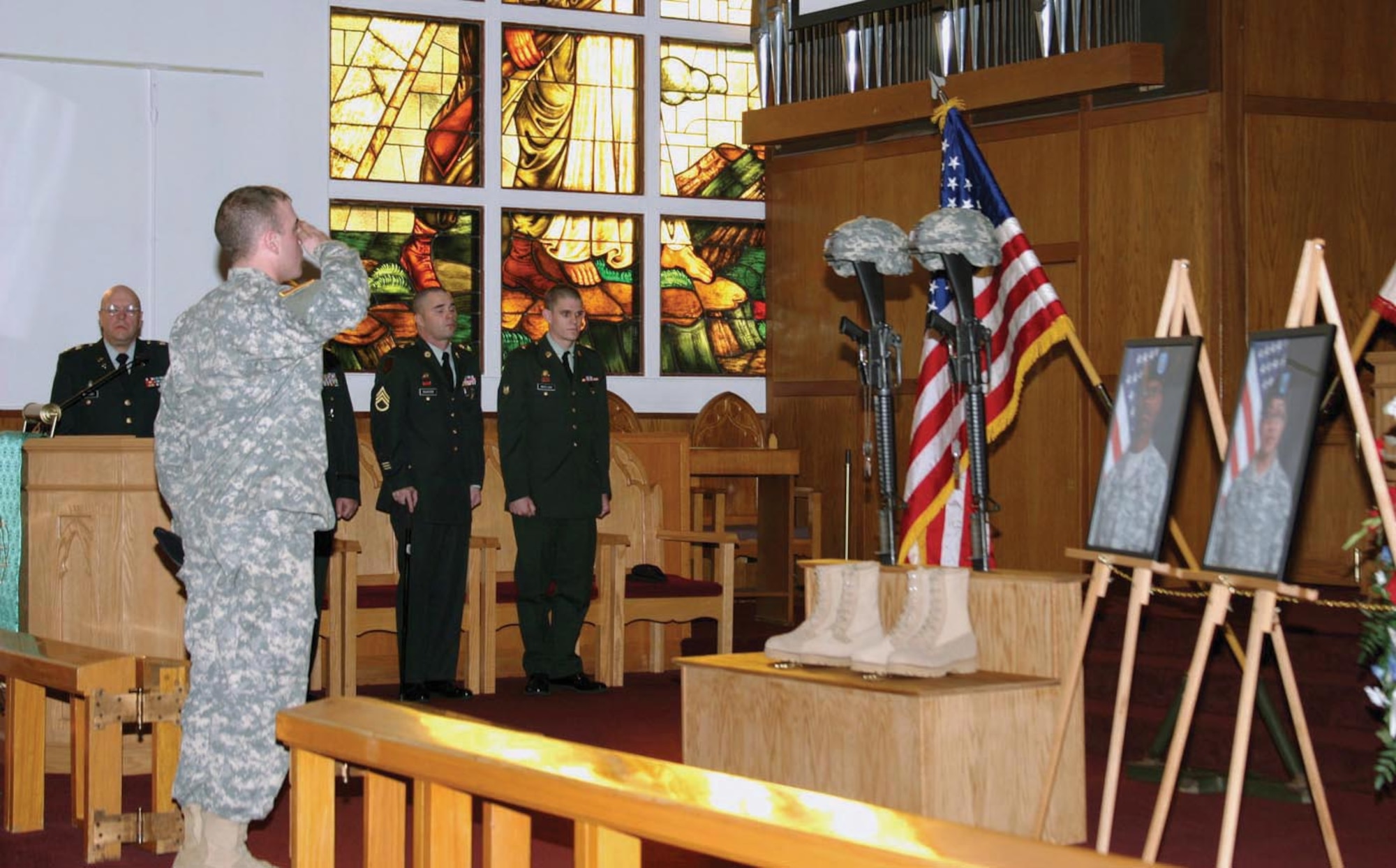 A Soldier saluts memorial photos of Pfc. William Dawson and PFc. Jaysine Petree, 17th Combat Sustainment Support Battalion, Oct. 12, at Soldiers' Memorial Chapel. (U.S. Army Photo/Spc. Tamika Dillard)