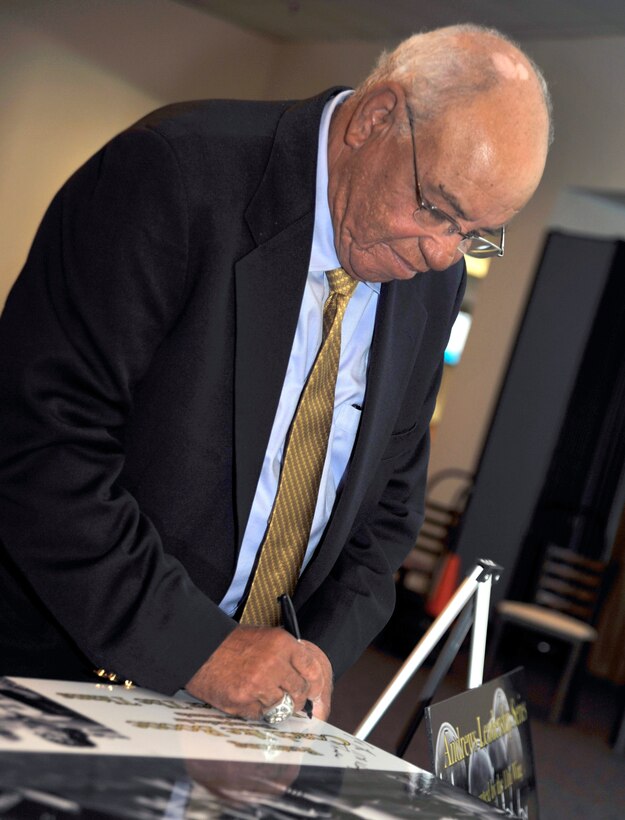 Herman Boone, former coach for the T. C. Williams High School football team that served as inspiration for the film 'Remember the Titans', signs a poster for the 11th Wing at the Joint Base Andrews Community Activity Center Oct. 21, 2010.  Mr. Boone was invited to the installation to give a speech as part of the base leadership series which invites speakers to come address the troops.  (U.S. Air Force photo/Staff Sgt. Christopher A. Marasky)