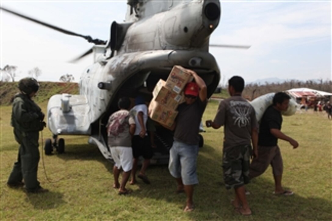 Victims of Super Typhoon Megi unload humanitarian aid supplies from a U.S. Marine Corps CH-46 Sea Knight helicopter in Divilacan, Isabela province, Philippines, on Oct. 22, 2010.  U.S. and Filipino military personnel conducted initial recovery assistance in the areas affected by the typhoon.  