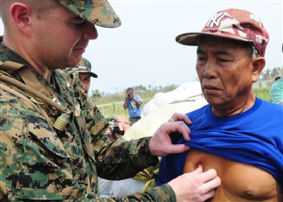 U.S. Navy Lt. John M. Tinjum (left), a medical officer assigned to the 31st Marine Expeditionary Unit, examines a man for injuries at an airfield in northern Luzon, Philippines, after Typhoon Juan struck the area on Oct. 22, 2010.  