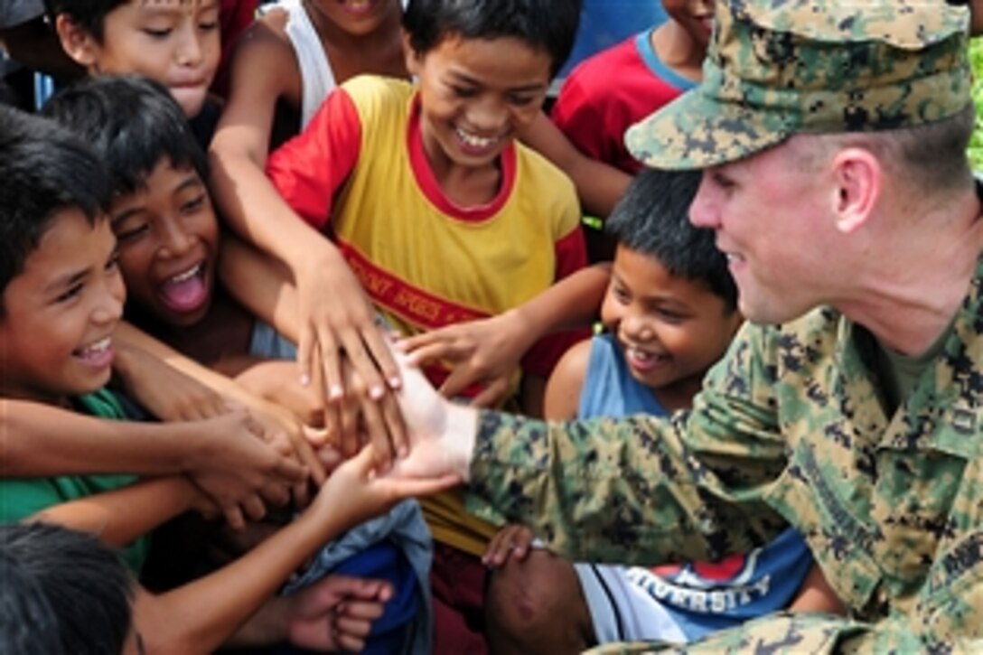 U.S. Marine Corps Capt. Bill Woodward says goodbye to Philippine children after assisting with the delivery of food following a typhoon in northern Luzon in the Philippines, Oct. 22, 2010. Woodward is assigned to the 31st Marine Expeditionary Unit.