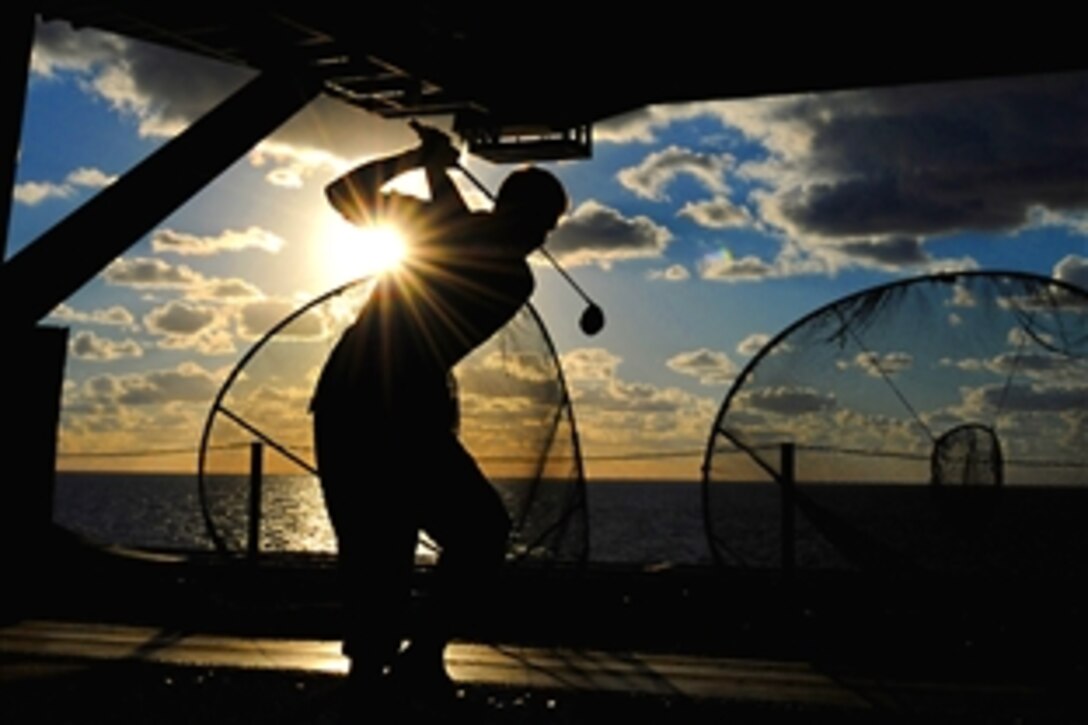 A U.S. Navy sailor aboard the USS George H.W. Bush hits a golf ball in the ship's hangar bay in the Atlantic Ocean, Oct. 24, 2010. 