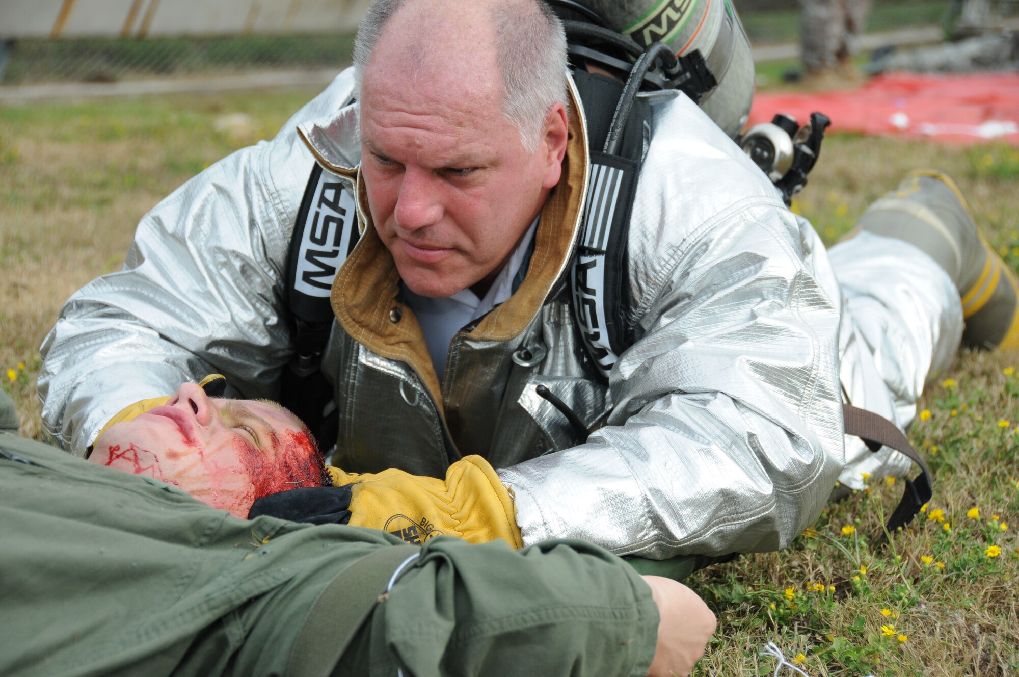 Vince Davis, Keesler Fire Department’s hazmat safety officer holds Airman Basic Joshua Hagen, a 338th Training Squadron student’s head steady while the medical triage officer retrieves a neck brace to stabilize his neck in Tuesday's major accident response exercise.  During the exercise a C-130J made a hard landing, lost engine power and crashed into a six-passenger van, coming to rest on the Triangle track north of Alho Manor.  The scenario also included a spill from chemicals on the aircraft, hydraulic fluid and JP-8 fuel.  Three people "died" and 30 were "injured" in the accident, part of this week's Air Education and Training Command Compliance Inspection.  (U.S. Air Force photo by Kemberly Groue)