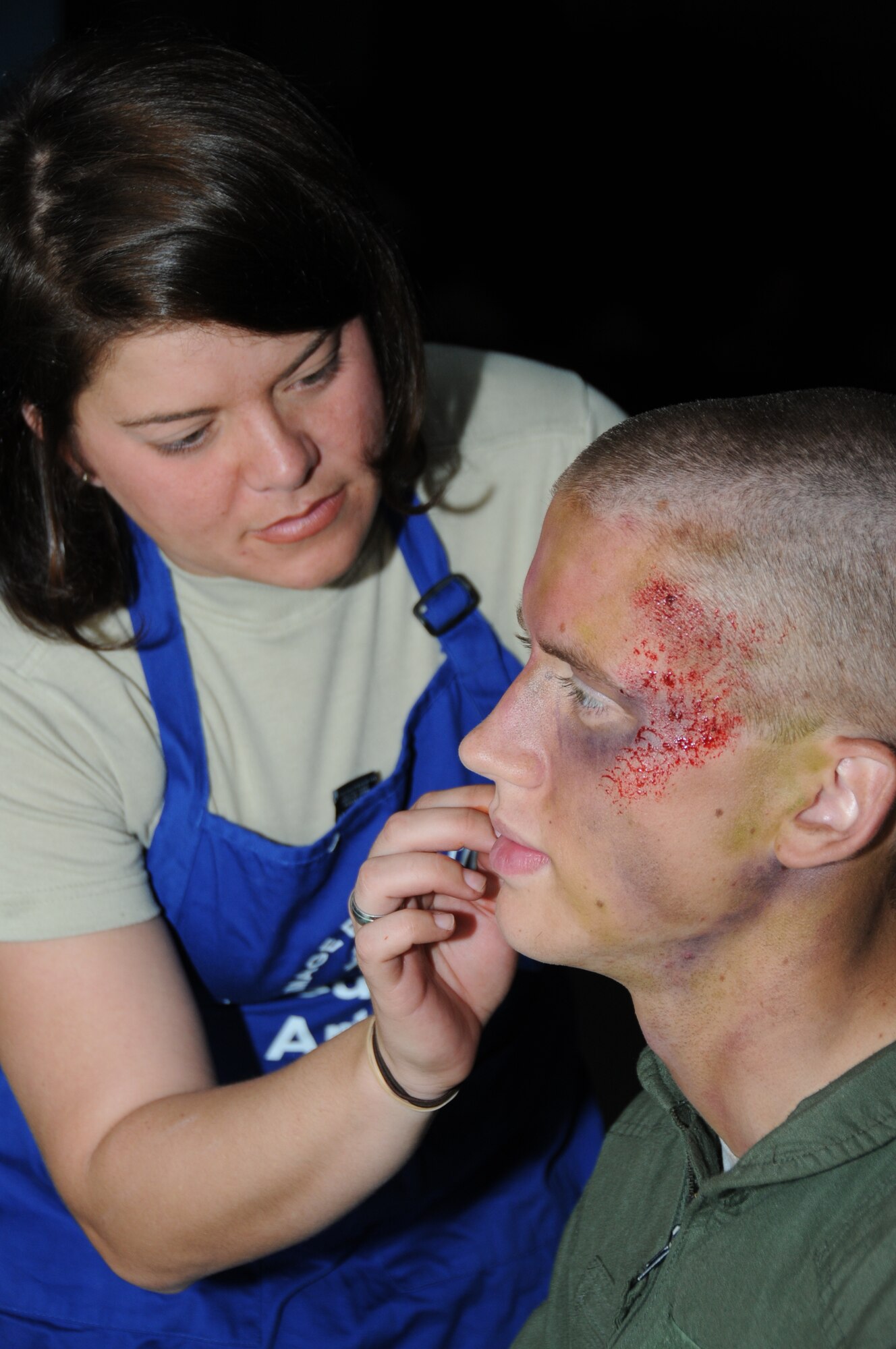 Staff Sgt. Cassandra Day, 81st Dental Squadron, applies moulage to Airman Daniel Parker, a 338th training squadron student’s face for a more visual effect in Tuesday's major accident response exercise.  During the exercise a C-130J made a hard landing, lost engine power and crashed into a six-passenger van, coming to rest on the Triangle track north of Alho Manor.  The scenario also included a spill from chemicals on the aircraft, hydraulic fluid and JP-8 fuel.  Three people "died" and 30 were "injured" in the accident, part of this week's Air Education and Training Command Compliance Inspection.  (U.S. Air Force photo by Kemberly Groue)