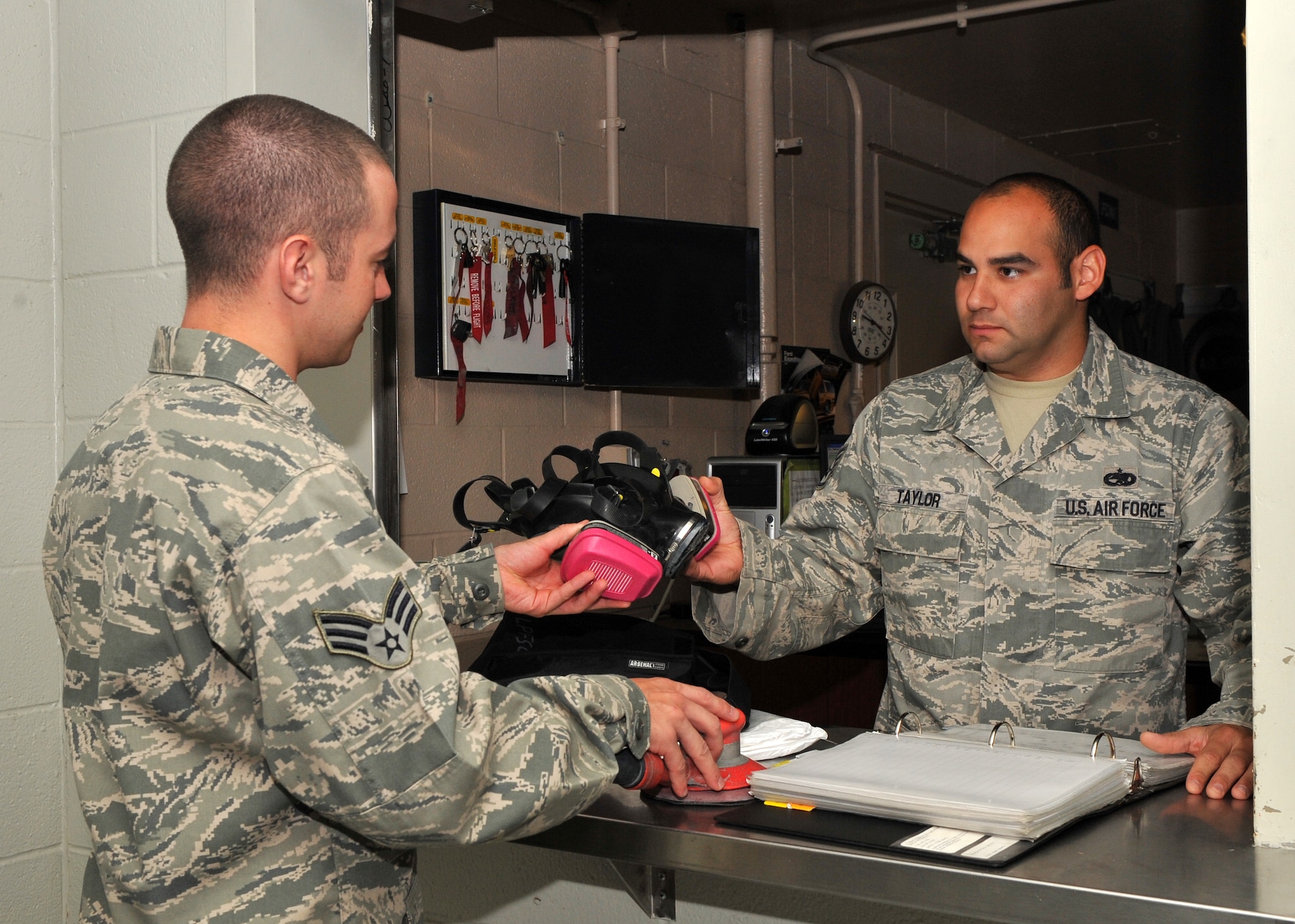 Senior Airman Dakota Phillips, 19th Equipment Maintenance Squadron corrosion control journeyman, checks out personal protective equipment Oct. 22 from Staff Sgt.  Sam Taylor, 19th EMS tool crib NCO-in-charge. Individuals performing corrosion control must wear a Tyvek suit, full-face respirator and other personal protection equipment. (U.S. Air Force photo by Senior Airman Gul Crockett)
