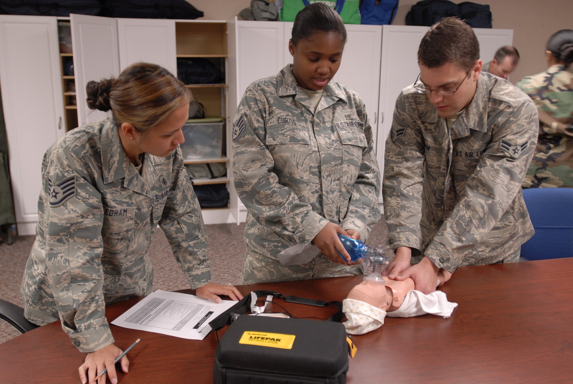 Staff Sgt. Dithma Needham (left), CPR instructor and aerospace physiology technician with the 21st Aerospace Medicine Squadron observes Staff Sgt. Melanie Curtis, aerospace physiology technician with the 21 AMDS, and Airman 1st Class Nathaniel Pepin, aerospace physiology technician with the 21 AMDS, as they practice cardiopulmonary resuscitation on an infant-mannequin. (U.S. Air Force photo/Airman 1st Class Jessica Hines)