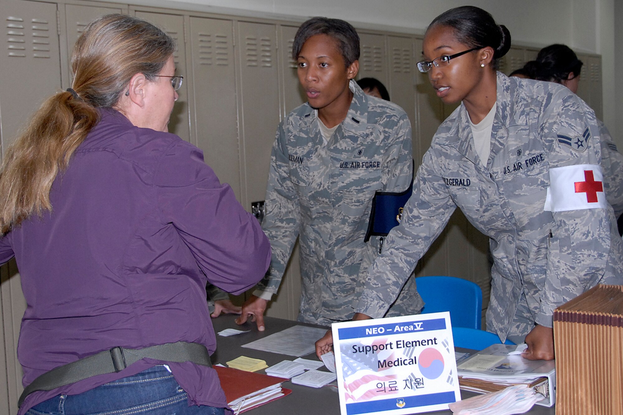 1st Lt. Alecia Doeman and Airman 1st Class Julia Fitzgerald, both from the 51st Medical Operations Squadron, complete a medical inquiry with a woman at Osan Air Base, Republic of Korea Oct. 22. The inquiry was apart of an annual Non-combatant Evacuation Operation exercise. The two-day exercise tested the base's ability to process and evacuate non-combatant base personnel and dependents in the event of an emergency. (U.S. Air Force photo/Staff Sgt. Eunique Stevens)   
