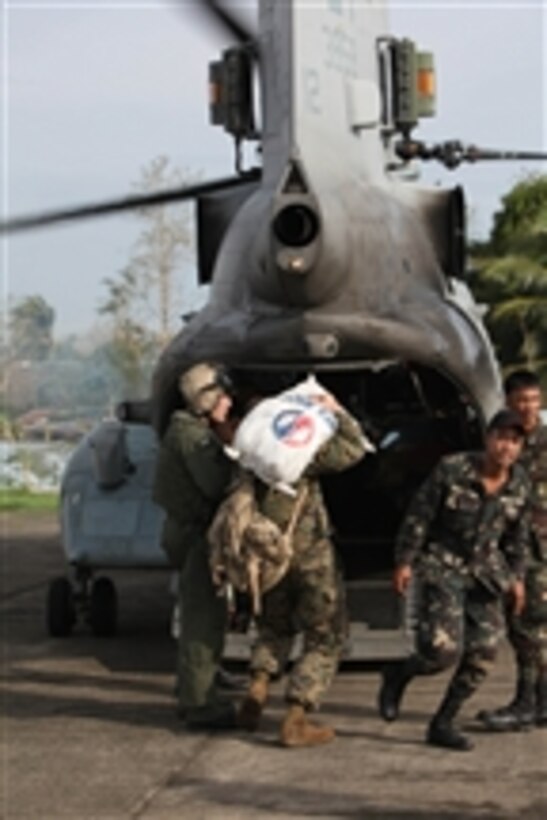U.S. Marines (left) and Philippine service members load humanitarian aid supplies onto a U.S. Marine Corps CH-46 Sea Knight helicopter in the Philippines for delivery to areas in the nation’s Isabela province affected by Super Typhoon Megi on Oct. 21, 2010.  