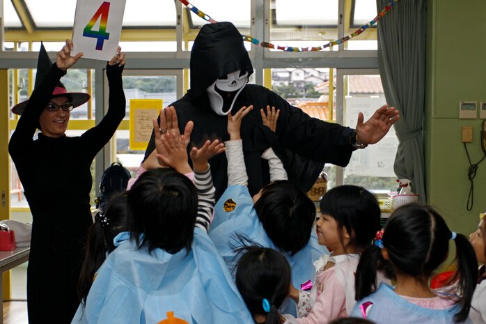 Cpl. Jacklyn White, a station American Forces Network broadcaster, holds a card up as part of a game played during a visit to Midoro Hoiken School in Iwakuni, Oct. 26. Approximately 10 service members visited the school to play and teach Western Halloween traditions to the school students.