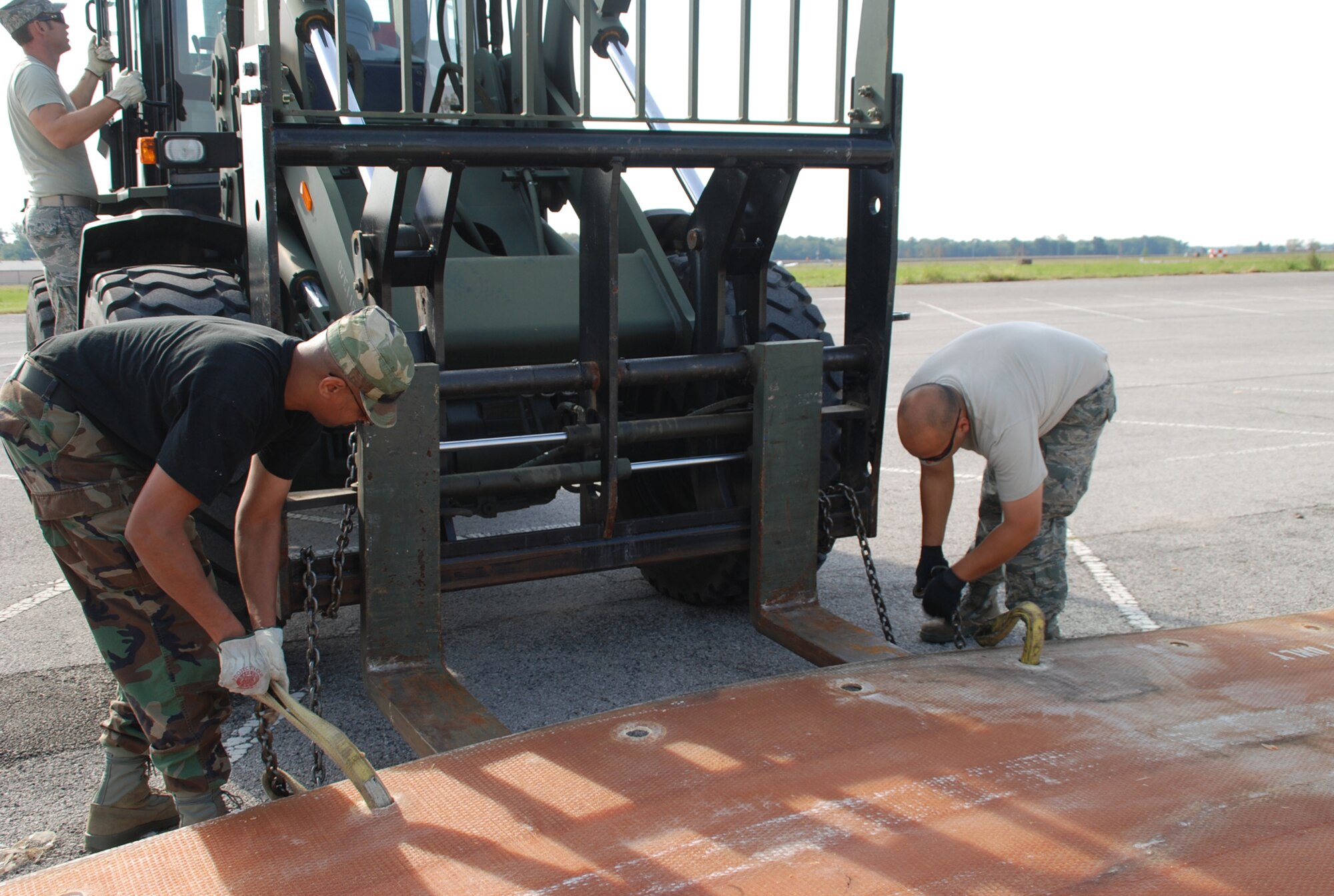 932nd Airlift Wing Civil Engineering Squadron members attach straps and chains in
preparation to stretch a mat to line up with a second mat used to cover a simulated crater.  The fold-out, fiberglass mats can be quickly deployed over craters and large holes, keeping the runway usable for aircraft.  (U.S. Air Force photo/Tech. Sgt. Dan Oliver)