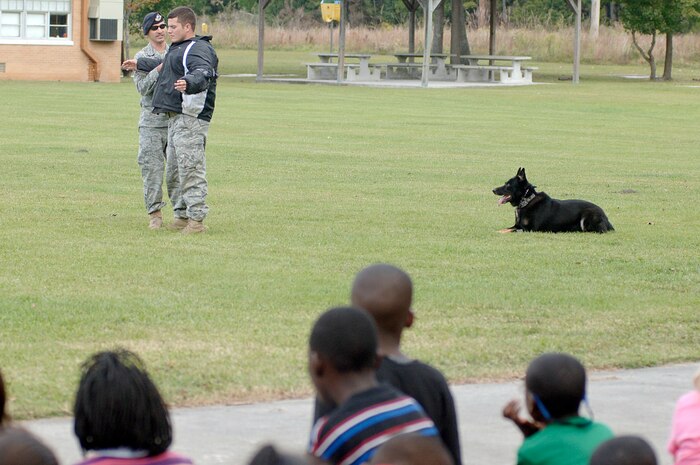Students and faculty at Lambs Elementary watch as U.S. Air Force Senior Airman Brandon Edwards, left, Senior Airman Joel Patterson, right, and military working dog Waldo demonstrate how an aggressor is apprehended during a demonstration held at the school Oct. 26, 2010. The working dog demonstration was part of Red Ribbon Week, which is the nation's oldest and largest drug prevention program, reaching millions of Americans every year. Airmen Edwards and Patterson are both military working dog handlers with the 628th Security Forces Squadron. (U.S. Air Force photo/Staff Sgt. Marie Brown)