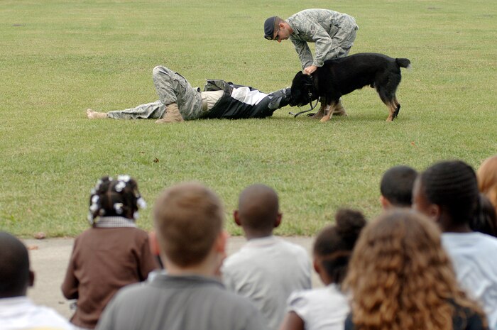 Students and faculty at Lambs Elementary watch as U. S. Air Force Senior Airman Brandon Edwards, right, and Senior Airman Joel Patterson, left, demonstrate how military working dog Waldo takes down an aggressor during a demonstration held at the school Oct. 26, 2010. The working dog demonstration was part of Red Ribbon Week, which is the nation's oldest and largest drug prevention program, reaching millions of Americans every year. Airmen Edwards and Patterson are both military working dog handlers with the 628th Security Forces Squadron. (U.S. Air Force photo/Staff Sgt. Marie Brown)