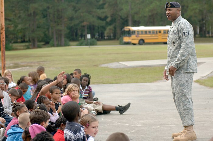 U.S. Air Force Staff Sgt. Ramon Alexander speaks to the students and faculty at Lambs Elementary School about a tip that was received regarding drugs on the premises as part of a scenario for a dog demonstration during Red Ribbon Week Oct. 26, 2010. Members of Joint Base Charleston visited local elementary schools during the week-long campaign to raise public awareness and mobilize communities to combat tobacco, alcohol and drug use. Sergeant Alexander is a military working dog handler with the 628th Security Forces Squadron. (U.S. Air Force photo/Staff Sgt. Marie Brown)