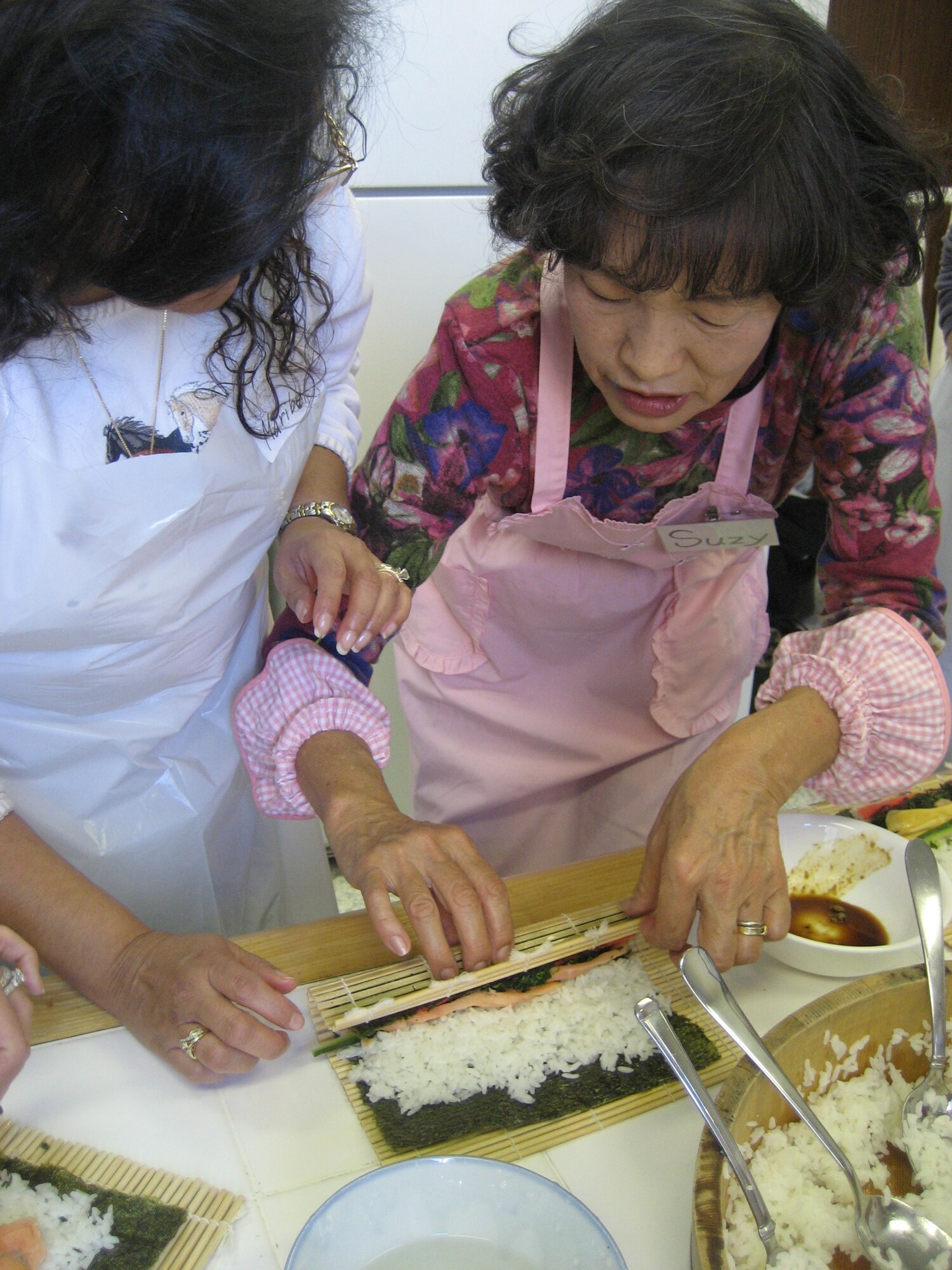 YOKOTA AIR BASE, Japan -- Suzy Fukuoka (right) shows Maribel Edwards the correct way to complete maki-zushi, or a sushi roll, here Oct. 27.  Mrs. Fukuoka, the class instructor has volunteered with the 374th Force Support Squadron’s Airman and Family Readiness Center for the past six years and has volunteered at Yokota Air Base for nearly 20 years.  (U.S. Air Force photo/Capt. Tania Bryan)