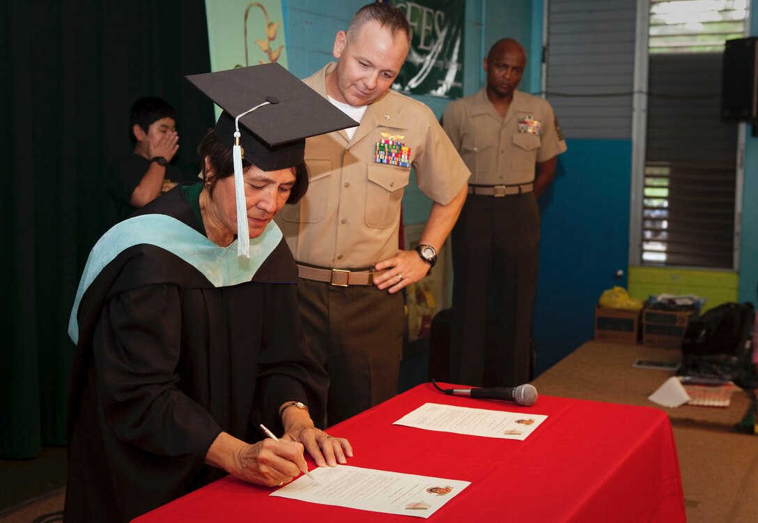 Lt. Col. Patrick R. Owens, commanding officer, Headquarters Battalion, Marine Corps Base Hawaii, watches as Alexis Kane, principal, Puohala Elementary School, signs an Adopt-A-School Program contract at the school in Kaneohe, Hawaii, Oct. 27. The relationship between HQBN and the school affords Marines the opportunity to mentor students, and help the school with school activities and maintenance. “The partnership is good for both the community and our base,” said Owens. “It’s important for the community to know we are serving our country, and we care about them.”