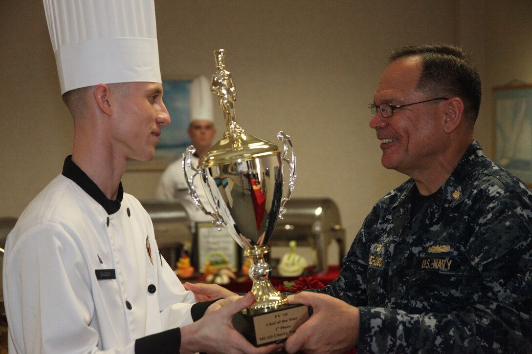 Capt. Edgardo Perez-Lugo, the Naval Health Clinic’s commanding officer, hands Cpl. Michael P. Gaudin the first place trophy for Cherry Point’s annual chef of the year competiton at the mess hall here, Oct. 28. The three chefs in the competition were prior winners of chef of the quarter competitions.