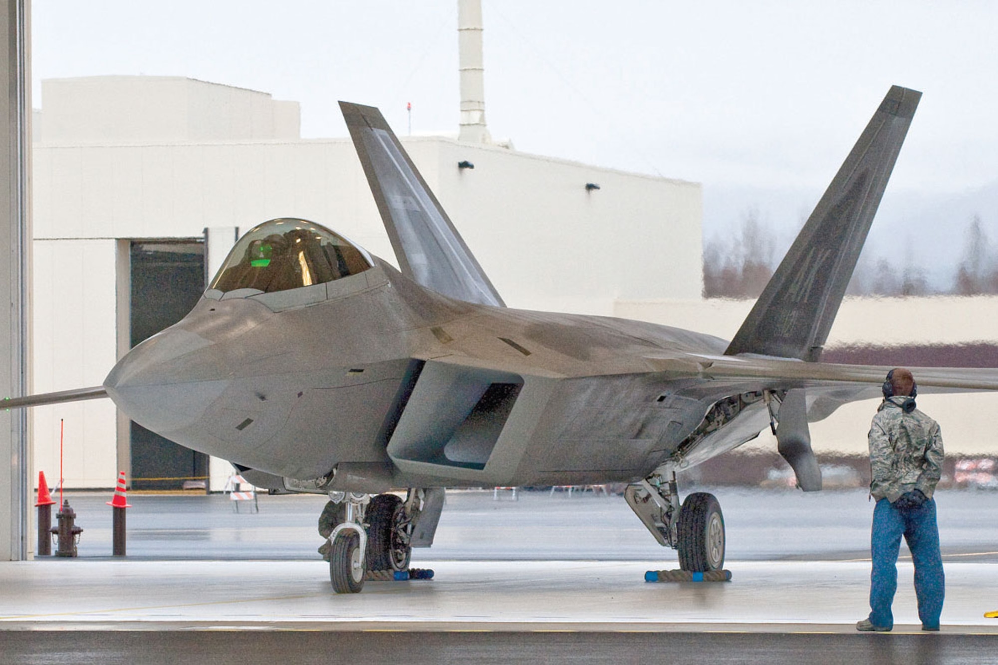 JOINT BASE ELMENDORF-RICHARDSON, Alaska – A crewchief,525 Fighter Squadron, waits to signal an F-22 Raptor out of the hanger Oct 25. Monday was the first day the 525 FS used their new aircraft shelters. The 15 attached hangers help improve their maintenance capability by sheltering the jets from the winter elements.  (U.S. Air Force photo/ Senior Airman Kristin High)
