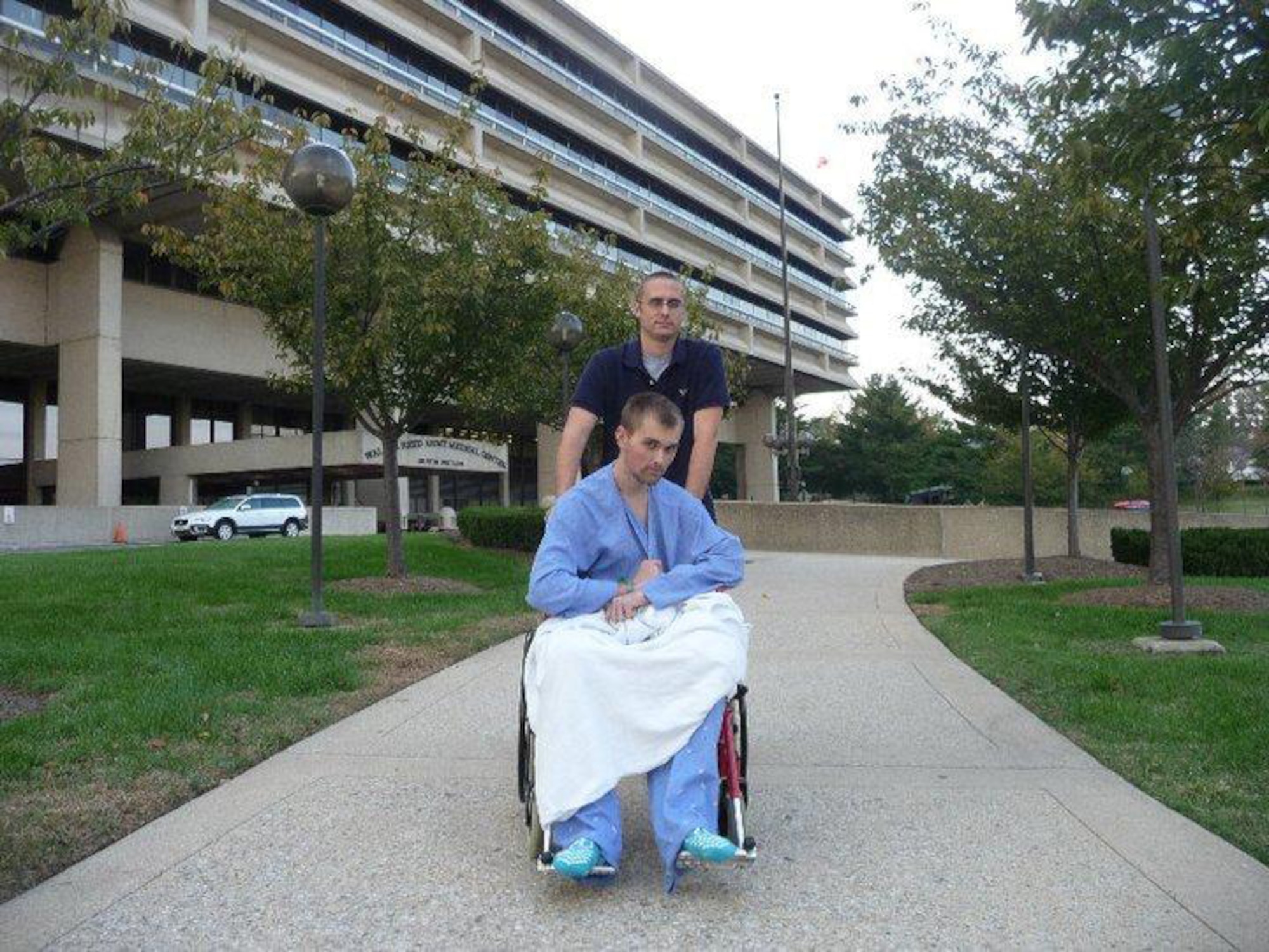 WASHINGTON, D.C. -- Senior Airman Erving Perkins wheels his wingman, Airman Colton Brown, out of Walter Reed Army Medical Center for the first time while recovering from an illness, Oct. 8, 2010.  Shortly after arriving at Joint Base Balad, Iraq, fluid was found in Airman Brown's lungs, drainage tubes were placed and he was medically evacuated from the Air Force Theater hospital to Germany. Airmen Perkins and Brown are both 4th Operation Support Squadron aircrew flight equipment technicians. Airman Perkins hails from Beacon, N.Y. and Airman Brown is from Hamilton, Ohio. (Courtesy photo)

