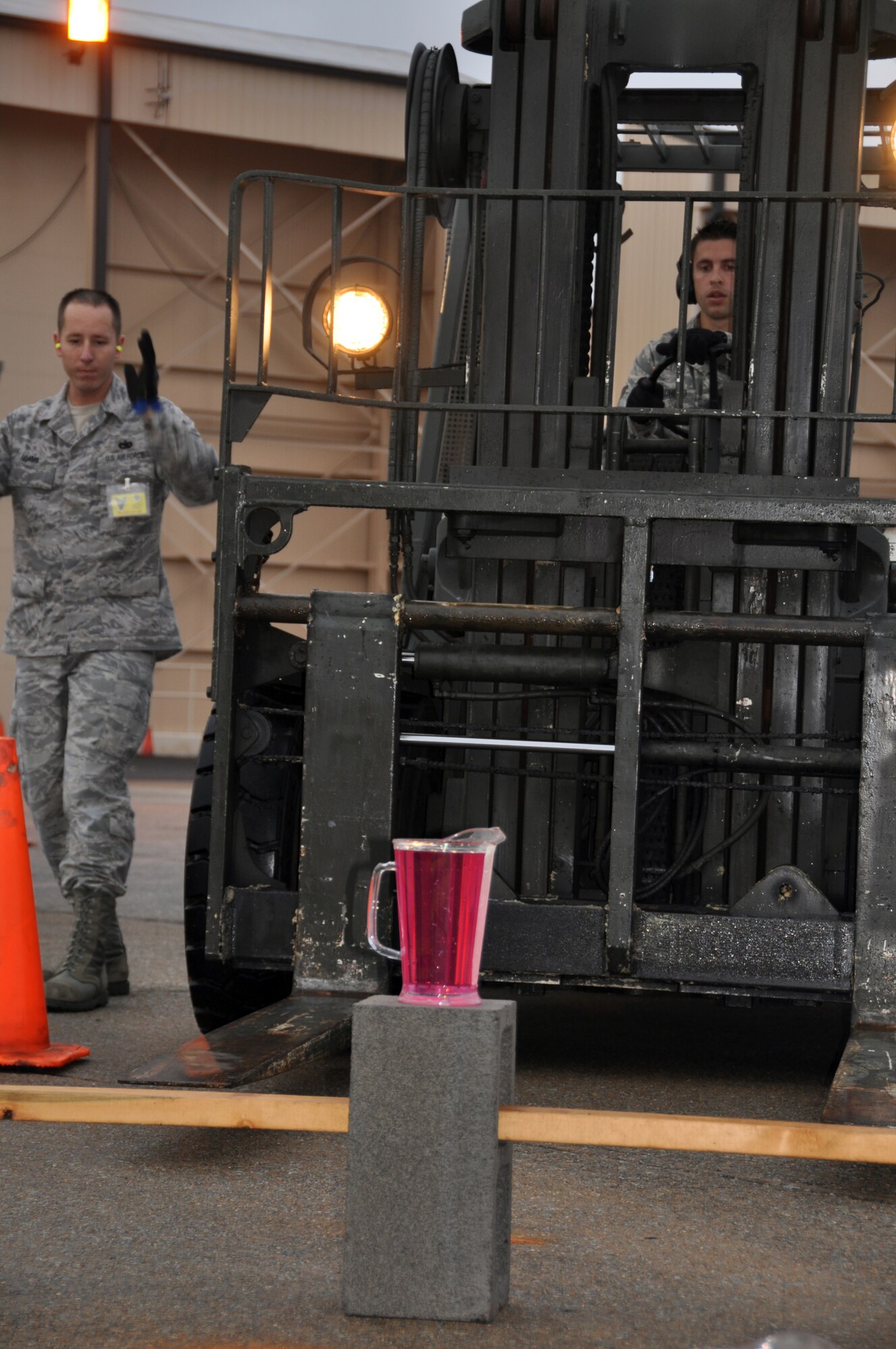 Tech. Sgt. Justin Adams (left) guides Senior Airman Sterling Broadhead, both of the 67th Aerial Port Squadron, through a driving course at AFRC's Port Dawg Challenge Oct. 29. In the timed event, Airman Broadhead had to maneuver a 10K forklift through cones without spilling the contents of the pitcher. (U.S. Air Force photo/Bryan Magaña)