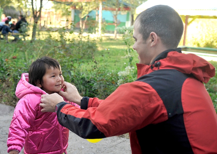 First Lt. Mike Capelle fits a winter coat on a girl Oct. 18, 2010, at the Solnyshko school near Vasilievka, Kyrgyzstan. Several Airmen who are deployed to the Manas Transit Center, Kyrgyzstan, visited the school to deliver cold weather items and spend time with the kids. (U.S. Air Force photo/Staff Sgt. J.G. Buzanowski) 