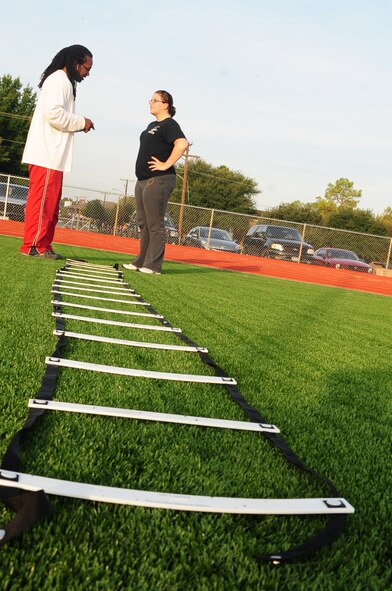 SHREVEPORT, La. -- Tedric Johnson, Health and Wellness Center trainer, instructs Airman 1st Class Alyna Roberts 2nd Medical Support Squadron, how to properly perform an exercise at Captain Shreve Stadium Oct. 27. Mr. Johnson runs the HAWC's 'rookie runner' program, designing dynamic workouts targeted to pass a physical training test. (U.S. Air Force photo/Senior Airman Joanna M. Kresge)
