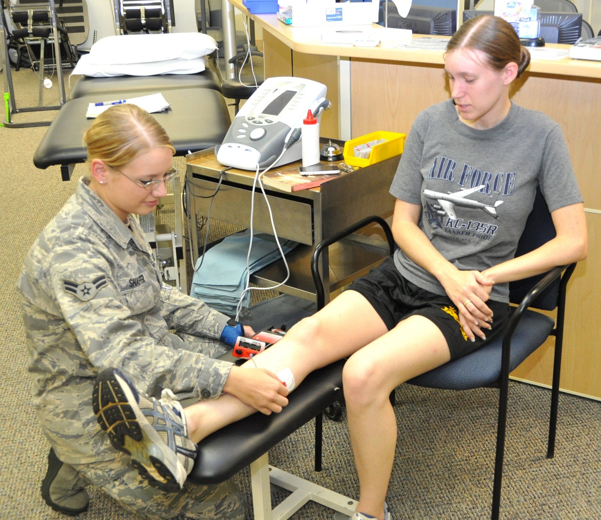 Airman 1st Class Kurstie Shaffer connects leads from an iontophoresis unit to 1st Lt. Sarah Reeves’ leg. The equipment forces anti-inflammatory medication through the
skin to an affected area. Lieutenant Reeves is a member of the 81st Training Group.  (U.S. Air Force photo by Steve Pivnick)