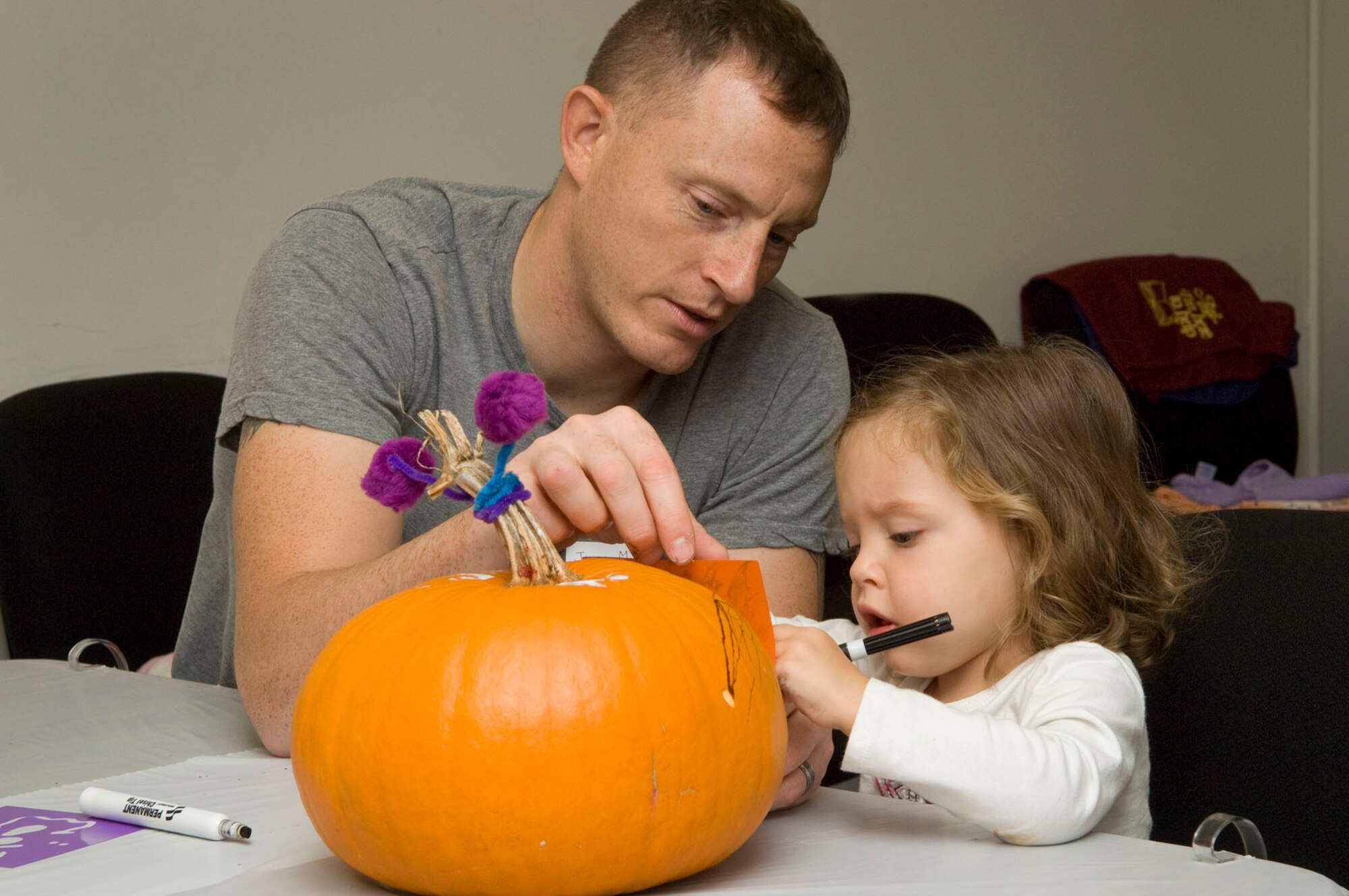 HANSCOM AIR FORCE BASE, Mass. - Rylee MacGuire and her father, Army Sgt. Jason MacGuire, draw designs on a pumpkin at the Base Library on October 26. Families brought their own pumpkins to decorate and bring home to display. (U.S. Air Force photo by Mark Wyatt)