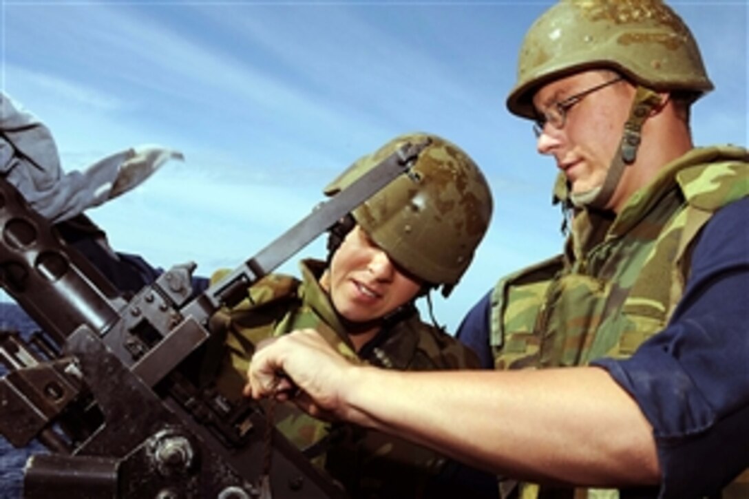 U.S. Navy Petty 2nd Class Neil Hodges and 2nd Class James prepare a .50-caliber machine gun for a night live-fire exercise aboard the guided-missile destroyer USS Mitscher in the Atlantic Ocean, Oct. 25, 2010. The Mitscher is part of the George H.W. Bush Carrier Strike Group and is conducting training operations.