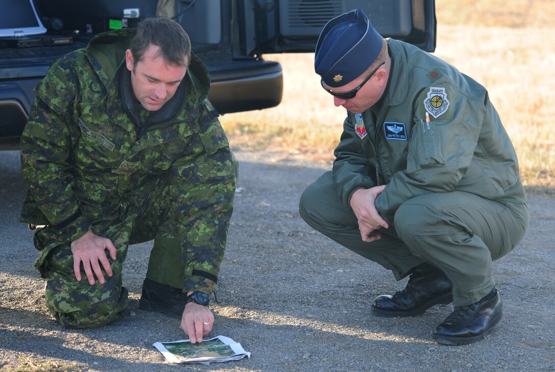 ELLSWORTH AIR FORCE BASE, S.D. -- (Right to left) Maj. Jan-Peter Linch, 28th Bomb Wing wing weapons officer, and Sgt. Aaron Cutler, 1st Regiment Royal Canadian Horse Artillery, look over a map during a joint-nation training mission between B-1 aircrew and Canadian joint terminal attack controllers in Alzada, MT, Oct. 28.  The training provided a different perspective for B-1 pilots and JTAC personnel by combining joint-nation training with air to ground support. (U.S. Air Force photo/Airman 1st Class Anthony Sanchelli)
