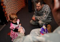 MINOT AIR FORCE BASE, N.D. -- Mackenzie, 18 months, and her father, Staff Sgt. Kevin Patrick, 5th Force Support Squadron man power analyst, receives candy from Airman 1st Class Haley Johnson, 5th Comptroller Squadron military pay technician, during a ‘trick or treating’ event at the PRIDE building here Oct. 29. Events like these keep Airmen and family morale and spirits high as cold and snow become a mainstay for Team Minot. (U.S. Air Force photo by Senior Airman Benjamin Stratton)