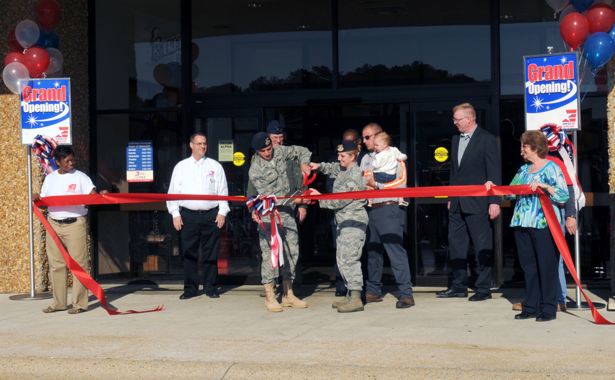 Senior Airman Chrissta Koustvalas, 14th Security Forces Squadron, and Airman 1st Class Justin Lopez, 14th SFS, cut the ribbon at the grand re-opening of the Columbus AFB Exchange Oct. 21. Airman Koustovalas, along with her husband Tommy and young daughter, were chosen to represent the Airman and families AAFES support, while recently-returned from deployment Airman Lopez was chosen to represent the men and women AAFES supports overseas.