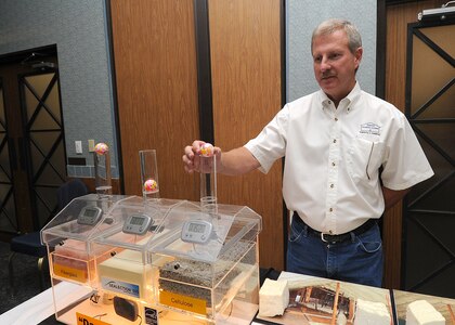Patrick Getzer, Superior Insulation Systems, demonstrates how insulation from his company blocks air, saving on heating and cooling costs by preventing heat and cold from entering a building. The colored ping pong ball demonstrates the effectiveness of his product. Numerous vendors provided displays of energy saving technologies during an Energy Fair at Randolph Air Force Base, Texas, Oct. 27.(U.S. Air Force photo/David Terry)