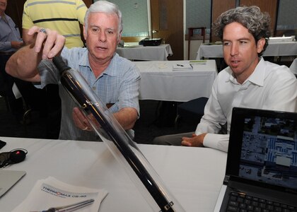 A solar hot water heater element is demonstrated by Bob Anderson of Rand Associates (left), and Hugh Daschbach, CincoSolar, during an Energy Fair at Randolph Air Force Base, Texas, Oct. 27. The one-day event provided Air Force personnel an opportunity to see various innovations in solar energy and energy savings technologies. (U.S. Air Force photo/David Terry)