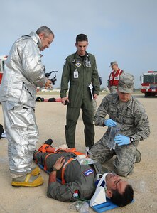 Thomas Gaffney, a Randolph firefighter, and Maj Jason Kelley, 359th Aerospace Medicine Squadron flight surgeon, look on while aerospace medical technician, Airman 1st Class Maxwell Lien prepares to insert an IV into an injured crew member during Randolph AFB aircraft accident and first responder exercise. 
( U.S Air Force Photo By Don Lindsey)