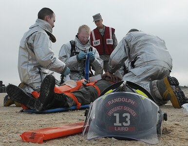 Senior Airman Ryan Laird and Mr. Kenneth Shepherd from the Randolph Fire Department assist Mr. Thomas Gaffney while he prepares an injured pilot for transportation after an aircraft accident during the base exercise simulating an aircraft accident.  
(U.S. Air Force Photo By Don Lindsey)