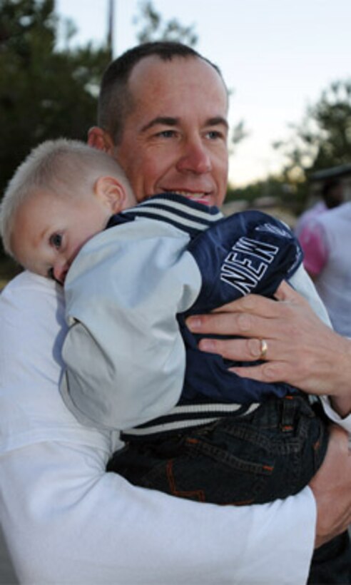 Cpl. Jonathan Lee, 73rd Transportation Company, 10th Transportation Battalion, 7th Sustainment Brigade, holds his young son as his wife talks about her experience fighting breast cancer.