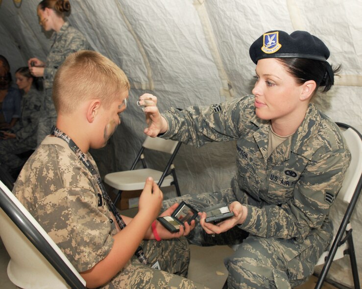 Senior Airman Sarah Thompson, 56th Security Forces Squadron member, applies camouflage to the face of Jack Davis, 9, during Operation KIDS held at Luke Air Force Base, Arizona, on October 23rd.  (U.S. Air Force photo/Staff Sgt. Louis Vega Jr.)