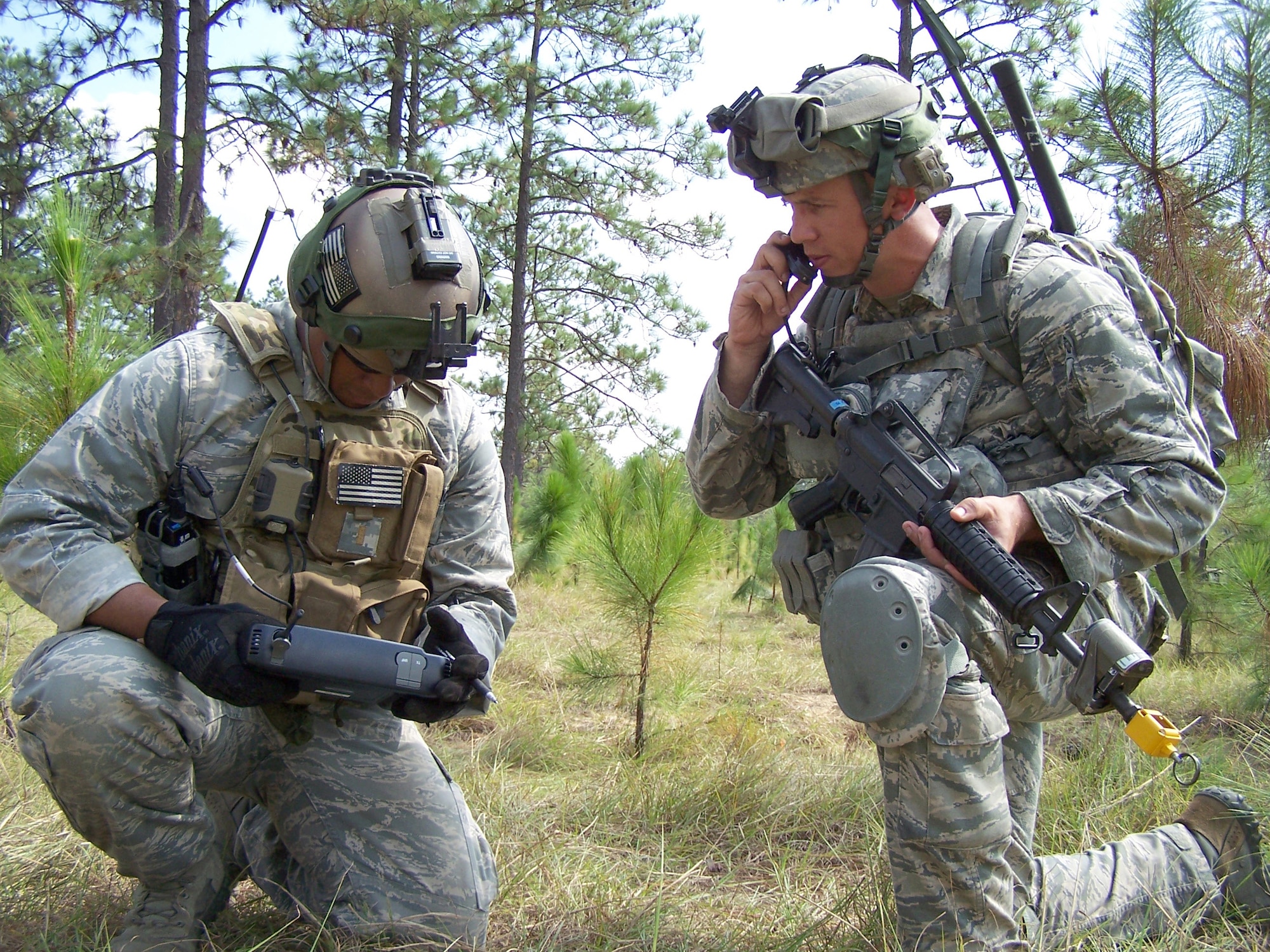 FORT POLK, LA. – Joint Terminal Attack Controller 2nd Lt. Brandon Pinto examines the picture on a ROVER5 (Remotely Operated Video Enhanced Receiver) during Green Flag East on Oct. 21. The Air Force Agency for Modeling and Simulation developed the capability to broadcast a combined live, virtual and constructive picture to ROVERs in the field. At right, Airman 1st Class Eric Hanson, a Radio Operator Maintainer and Driver, talks on the radio. (U.S. Air Force phot0/Noel Getlin)