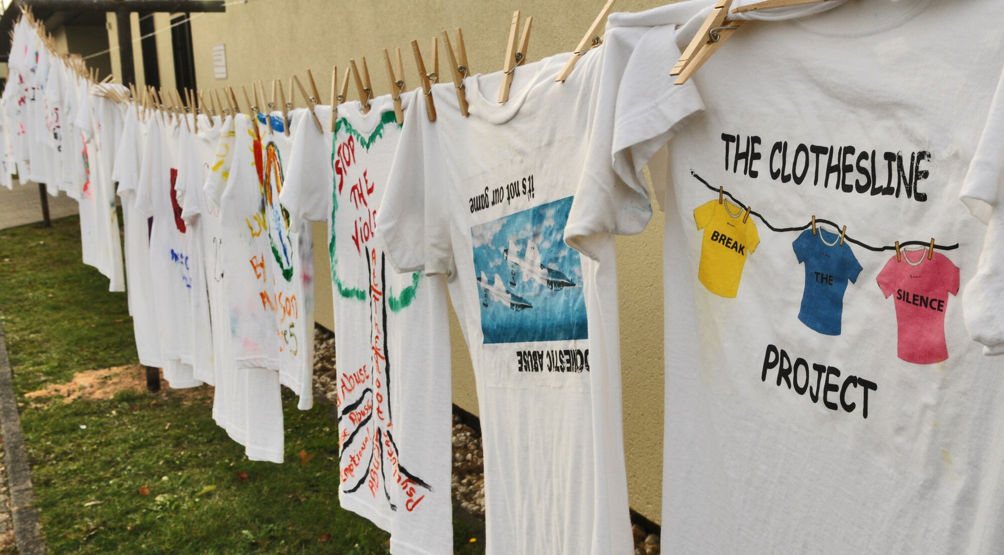 SPANGDAHLEM AIR BASE, Germany – A clothesline of 37 designed t-shirts hangs in front of the post office as part of the Clothesline Project Oct. 27. The Clothesline Project is a way for individuals affected by domestic violence to convey their emotions through artistically decorating a t-shirt to inform others about the dangers of domestic abuse. (U.S. Air Force photo/Senior Airman Nick Wilson)