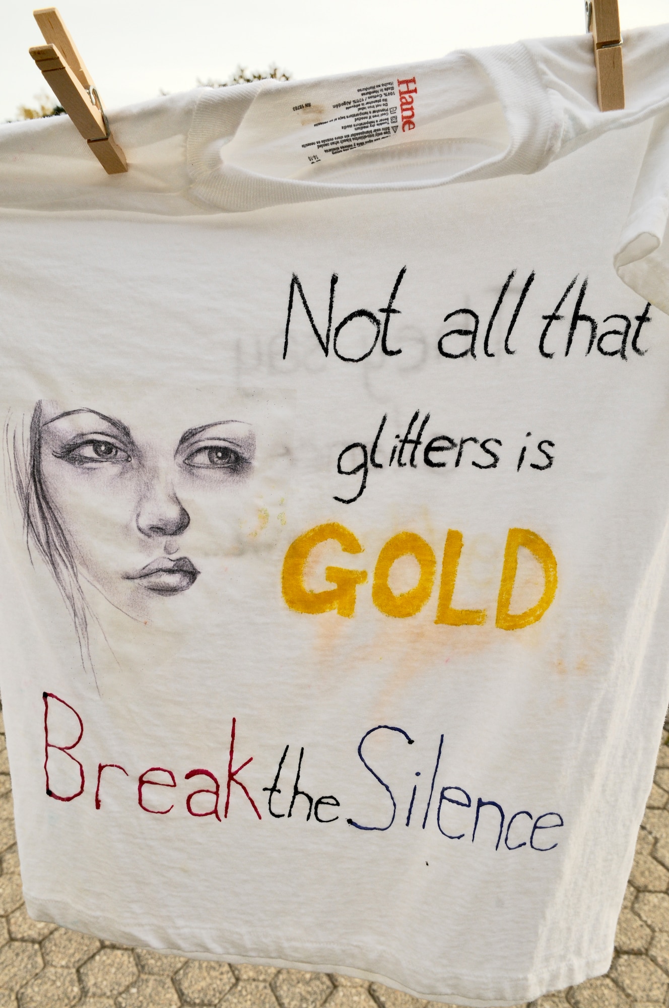 SPANGDAHLEM AIR BASE, Germany –One of 37 t-shirts designed by members from the Spangdahlem community hangs on a clothesline in front of the post office to promote domestic violence awareness as part of the Clothesline Project Oct. 27. The Clothesline Project is a way for individuals affected by domestic violence to convey their emotions through artistically decorating a t-shirt to inform others about the dangers of domestic abuse. (U.S. Air Force photo/Senior Airman Nick Wilson)
