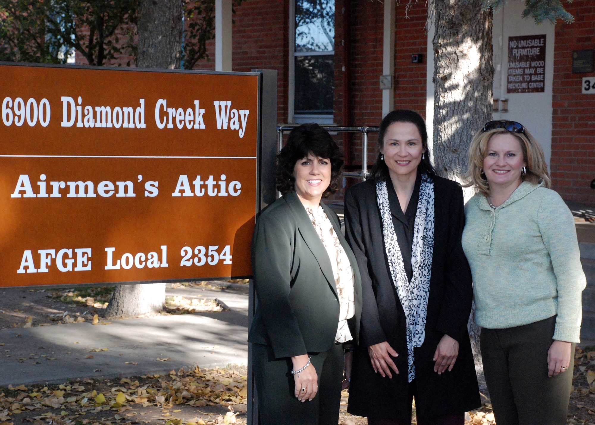 Ana Alston, Diana Boyle and Julie Tims pose for a photo outside the Airmen's Attic during Mrs. Alston's tour of F. E. Warren on Oct. 21. (U.S. Air Force photo by Staff Sgt. Mike Tryon)