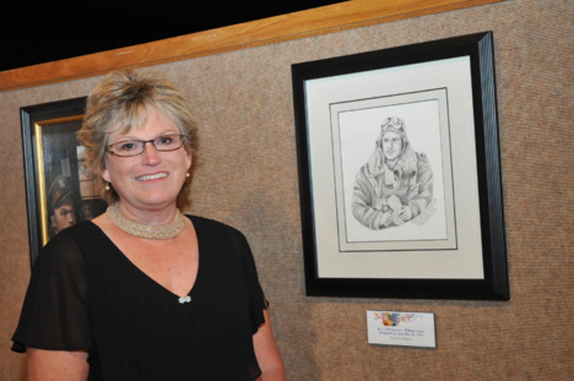 Elaine Balsley stands by a graphite sketch she made of her uncle, William James McQuoid Jr., who left Carnegie Tech in Pittsburgh to join the Army Air Corps as a B-17 tail gunner. He was killed on a final mission over Zwickau, Germany, in 1944. (Skywrighter staff photo/Niki Jahns)