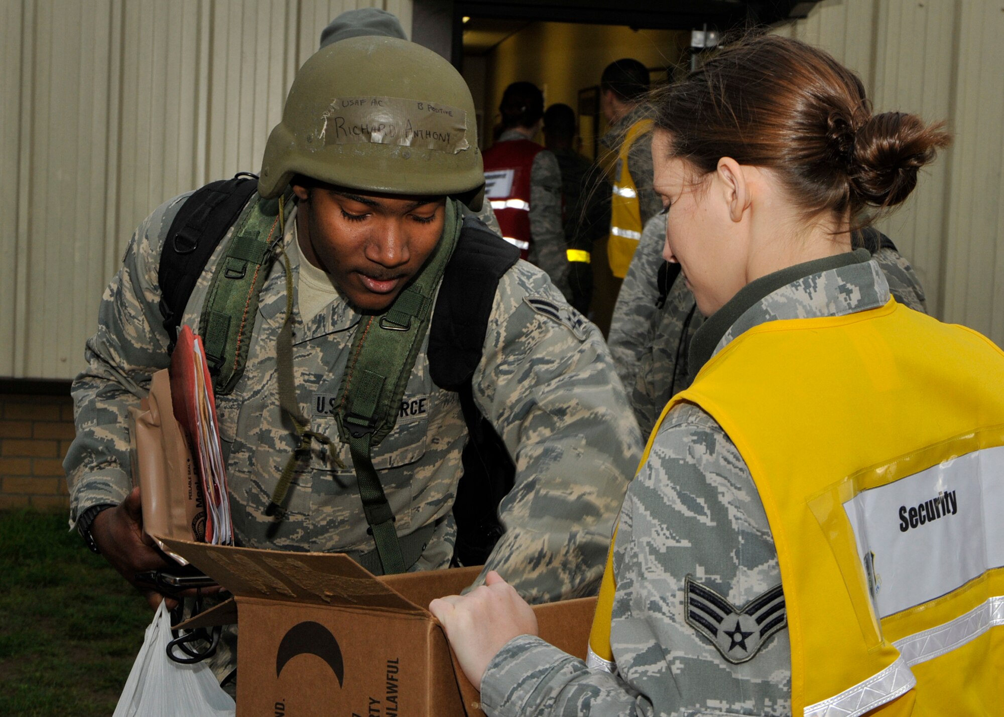 Airman 1st Class Anthony Richard, (left), 48th Emergency Maintenance Squadron Inspection Section journeyman, retrieves his electronic device from Senior Airman Christy Allen, 48th Logistics Readiness Squadron HAZMAT Pharmacy journeyman, who was on security detail during a mock deployment exercise at the 48th Logistics Readiness Squadron Liberty Wing Deployment Center on Oct. 26. This exercise was part of the Operational Readiness Inspection that lasted until the end of the week. (U.S. Air Force photo/Airman 1st Class Tiffany M. Deuel)