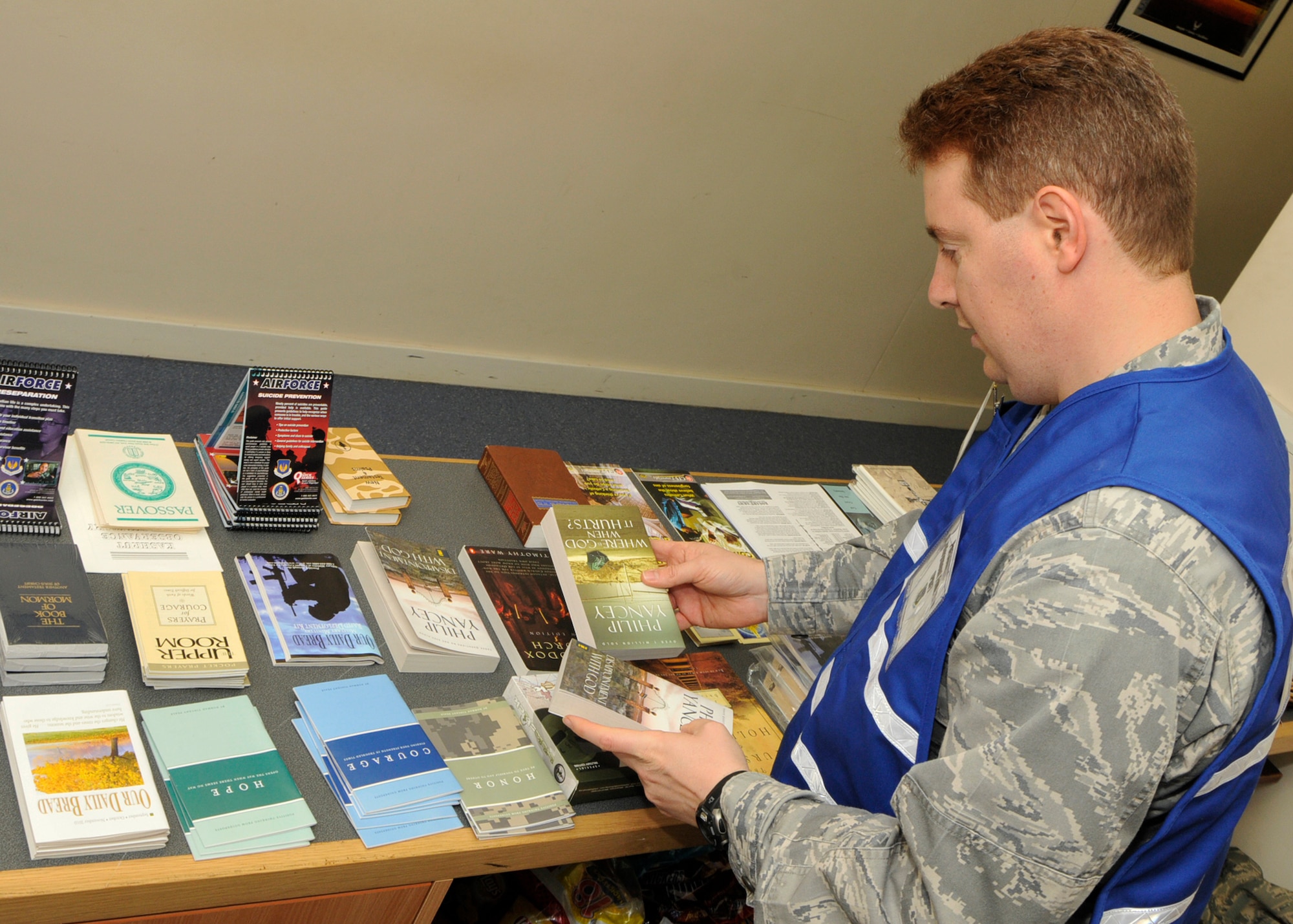 48th Fighter Wing Chaplain (Capt.) Matthew Glaros, sets out religious books at his booth on the processing line for Airmen participating in a mock deployment at the 48th Logistics Readiness Squadron Liberty Wing Deployment Center on Oct. 26. The simulated deployment was one part of the operational readiness. (U.S. Air Force photo/Airman 1st Class Tiffany M. Deuel)