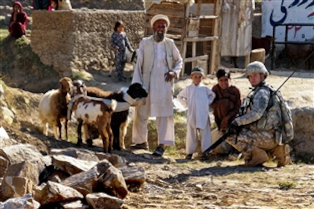 U.S. Army Staff Sgt. Jeremy Fehr speaks with Afghan children and their grandfather during a veterinary outreach program in the Marawara district in Afghanistan's Kunar province, Oct. 24, 2010. Local veterinarians treated nearly 200 goats, sheep and cattle. Fehr is assigned to the Iowa National Guard's 734th Agri-Business Development Team, which provided financial support, quality control and security during the event.