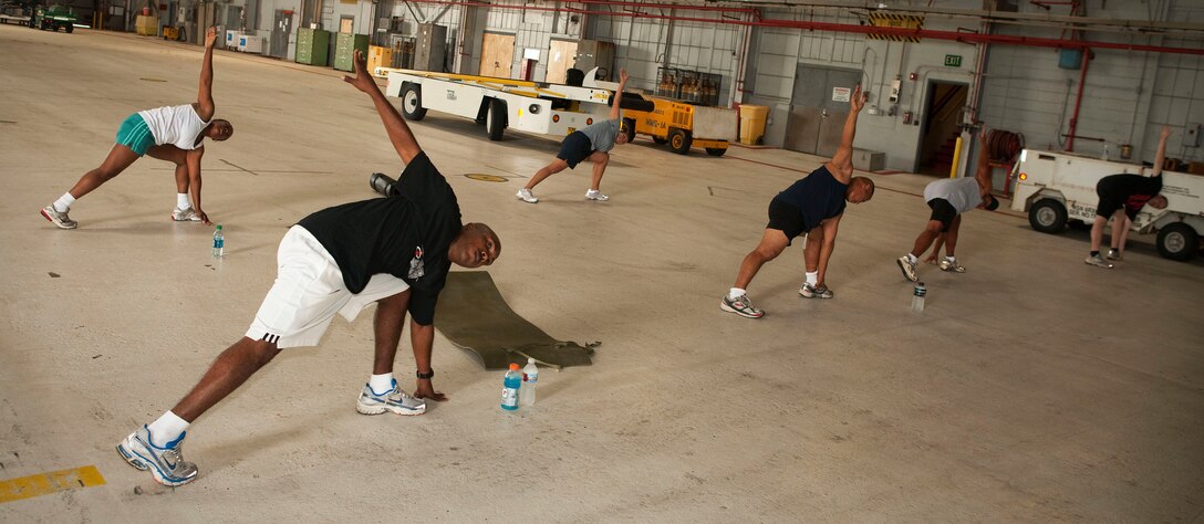 Marines and sailors assigned to Marine Corps Air Station Kaneohe Bay, Hawaii, stretch their way through the warm-up exercises of an Insanity Workout at Hangar 105 on MCAS, Oct. 29. “Marines benefit from this workout because it enables them to build cardiovascular endurance, strength, and aids in healthy weight loss,” said Gunnery Sgt. Katrina Michael, operations chief, C-20 Operations, MCAS.
