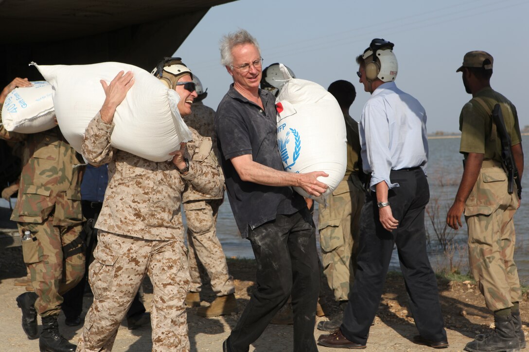 Newly-appointed U.S. Ambassador to Pakistan Cameron P. Munter (right), and Vice Adm. Mike LeFever, Office of the Defense Representative Pakistan commander, offload bags of flour from a U.S. Marine Corps CH-53E Super Stallion helicopter bringing flood relief supplies to Hassan Khan Jamali, a small village in Sindh province, Pakistan, Oct. 30, 2010. The ambassador visited Pano Aqil to see first-hand the Pakistan and U.S. military flood relief efforts conducted in Sindh Province, Pakistan, as well as to participate in a humanitarian mission bringing relief supplies to flood victims. 26th and 15th Marine Expeditionary Units have been flying CH-53E Super Stallion and CH-46 Sea Knight helicopters to isolated locations in Sindh province since early September and have transported more than 3.7 million pounds of relief supplies to 150 different locations in southern Pakistan.