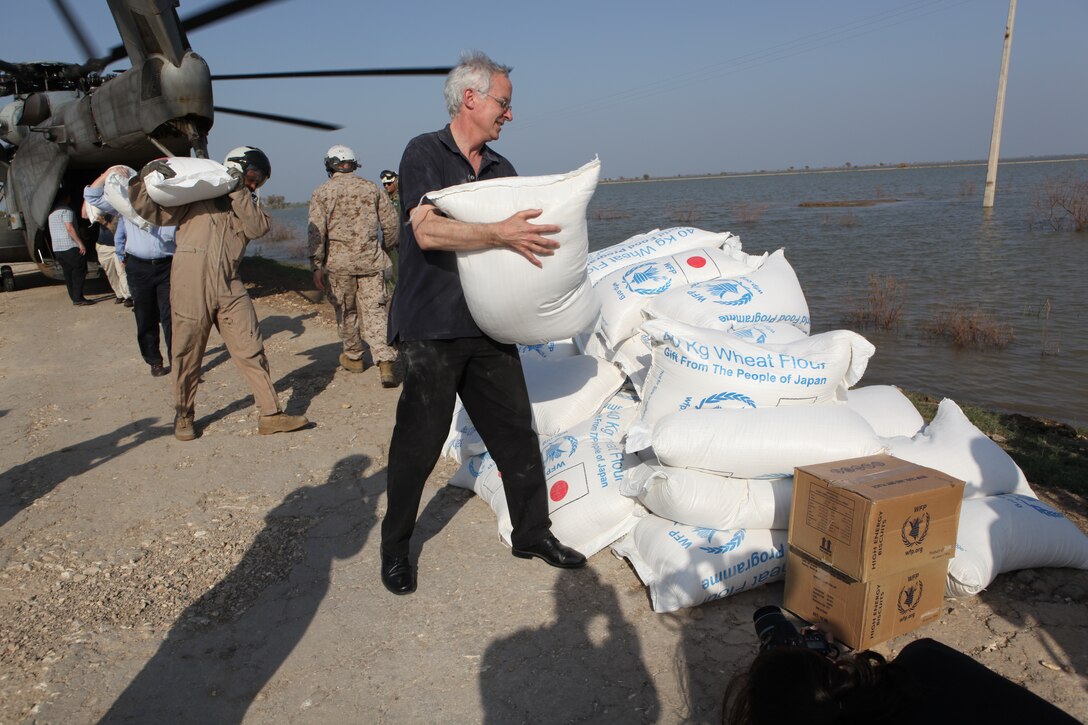 Newly-appointed U.S. Ambassador to Pakistan Cameron P. Munter (left) offloads a bag of flour from a U.S. Marine Corps CH-53E Super Stallion helicopter bringing flood relief supplies to Hassan Khan Jamali, a small village in Sindh Province, Pakistan, Oct. 30, 2010. The ambassador visited Pano Aqil to see first-hand the Pakistan and U.S. military flood relief efforts conducted in Sindh Province, Pakistan, as well as to participate in a humanitarian mission bringing relief supplies to flood victims. 26th and 15th Marine Expeditionary Units have been flying CH-53E Super Stallion and CH-46 Sea Knight helicopters to isolated locations in Sindh province since early September and have transported more than 3.7 million pounds of relief supplies to 150 different locations in southern Pakistan.