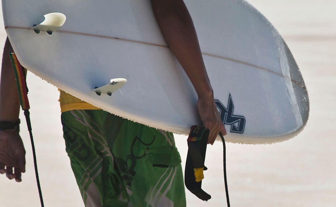 A competitor grips his surf board and walks back onto Pyramid Rock Beach following a heat in the Kuau Rockin’ Surf Competition on Marine Corps Base Hawaii, Oct. 31, 2010. “Being on base helps civilians understand and appreciate the sacrifices service members make,” said Billy Domingo, founder of Ainoskedu, a local sports apparel brand and competition sponsor. “Without the military, we wouldn’t be able to surf in these waters.”